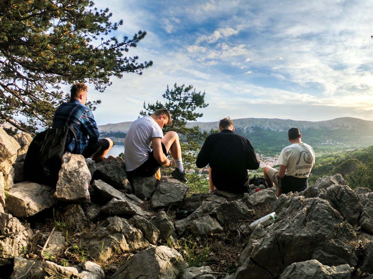 Four men sitting on rocks looking at a mountain